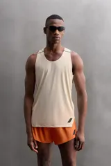 Camiseta deportiva sin mangas color beige, confeccionada en tejido técnico ligero y elástico con estructura perforada. Tiene cuello redondo amplio, sisas con acabados termofijados, bajo con aberturas laterales y logo estampado.