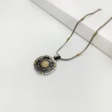 Conjunto de collar con cadena de eslabones plateada con detalles dorados y dije redondo con diseño de San Benito en plata y oro.