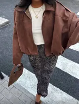 Bomber jacket color marrón de gamuza sintética, con cuello camisero, hombros caídos y elástico en la cintura.