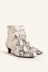 Bota corta de cuero vacuno con estampado animal print serpiente en tonos blanco y negro, con puntera fina y cierre trasero. Tiene taco chupete y suela de cuero.