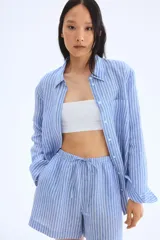 Short de lino celeste con rayas verticales blancas, cintura elastizada con cordón ajustable y corte holgado.