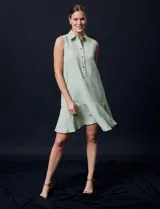 Vestido corto blanco de gasa, sin mangas, con cuello camisero, abertura central con botones y terminación de ruedo con volado.