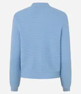 Cardigan de punto blanco, con cuello redondo, manga larga y cierre frontal de botones dorados. Posee dos bolsillos cuadrados en la parte delantera inferior.