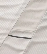 Remera deportiva de manga corta y cuello redondo, color beige claro, con textura acanalada vertical. Presenta detalles reflectantes en los hombros.