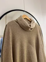Polerón color camel de corte oversize, con cuello drapeado y mangas largas caídas. La parte delantera es más corta que la trasera.