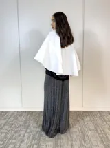 Capa corta blanca de paño con cuello solapa y cierre frontal con dos botones grandes. Mangas amplias tipo murciélago.