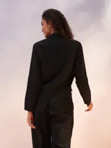 Blazer blanco de lino con doble botonadura y solapas de muesca. Tiene bolsillos delanteros con solapa y corte recto.