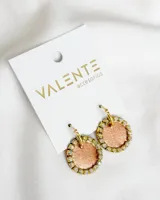 Par de aros colgantes con forma circular, con aro de acero dorado y pieza circular con centro color salmón brillante y borde con strass.