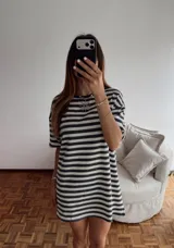 Vestido corto de tejido de punto a rayas horizontales en blanco y negro, con corte oversize y mini tajos laterales.