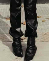 Bota de cuero negro con caña corta arrugada y taco fino.