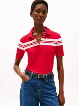 Chomba roja de piqué de algodón elástico con corte slim, cuello clásico, tapeta de seis botones y rayas horizontales blancas en el pecho y mangas. Logo de Tommy Hilfiger bordado en la manga.