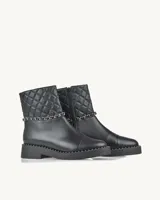 Bota corta negra de cuero con caña acolchada con diseño de rombos, detalle de cadena plateada y suela track con tachas.