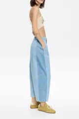 Pantalón vaquero de corte barrel, largo tobillero, tiro medio, con cierre frontal de botón y cremallera, bolsillos delanteros en costura, bolsillos de plastrón en la parte posterior y costadillos laterales.