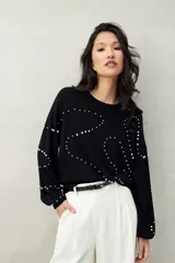 Sweater color beige con cuello redondo y mangas largas. Decorado con perlas sintéticas en forma de rombos.