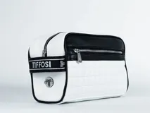 Neceser blanco con diseño acolchado a cuadros y detalles en cuero sintético negro. Tiene cierre superior y logo de la marca en el frente.