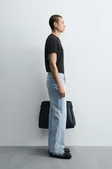 Pantalón de jean celeste de corte flare, con tiro medio, cinco bolsillos, cierre frontal con cremallera y botón, y bajo con acabado irregular.