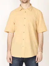 Camisa color amarillo claro de manga corta, estilo sport, con cuello clásico, cierre con botones de coco y bolsillo de parche en el pecho. Confeccionada en lino y algodón.