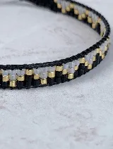 Pulsera tejida a mano con cuentas Miyuki en tonos blanco, negro y dorado.