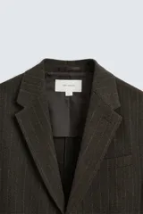 Blazer straight fit color marrón oscuro con finas rayas verticales claras. Confeccionado en tejido con lana de origen italiano. Cuello con solapas de muesca y manga larga acabada en puño con botones. Bolsillos de vivo en pecho y de solapa en cadera. Detalle de bolsillo interior. Bajo con aberturas en espalda. Cierre frontal de botonadura.