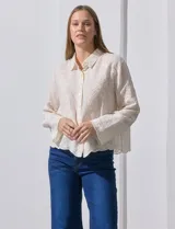 Camisa de manga larga color beige, con bordado tipo broderie, cuello con solapa y abertura central con botones.