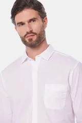Camisa de lino color beige, de manga larga, con cuello clásico y bolsillo en el pecho.