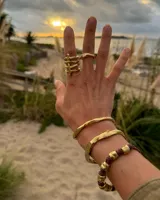 Brazalete rígido abierto de bronce con textura irregular.