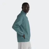 Campera deportiva New Balance Essentials, color verde azulado, con cierre frontal y cuello alto. Presenta costuras horizontales en la parte superior del pecho y bolsillos laterales con cierre.