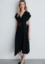 Vestido midi negro con escote en V, mangas cortas tipo kimono, falda acampanada con corte asimétrico y cinturón con hebilla metálica.