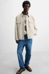 Sobrecamisa color beige de corte relaxed fit, con cuello solapa, manga larga con puños abotonados, bolsillos de plastrón con solapa en el pecho y bolsillos de vivo en la cadera. Cierre frontal con botones.