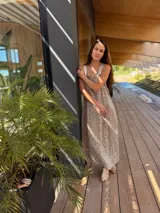 Vestido largo de tela metálica bordada color dorado, de corte suelto, con tajos laterales y breteles artesanales de cuero a tono.