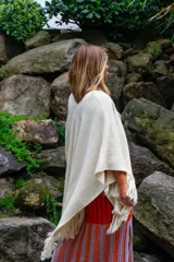 Ruana color crudo tejida a mano en punto arroz con lana merino. Presenta flecos en el borde inferior.