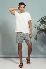 Short de baño con estampado de hojas en tonos grises y celestes, con cordón ajustable en la cintura y detalle de franja lateral con rayas rojas, blancas y negras.