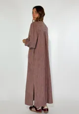 Vestido largo azul con rayas verticales en tonos beige y rojo, escote en V y mangas 3/4 abullonadas.
