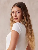 Remera blanca de rib, marca Tahari, con cuello redondo a la base y mangas cortas.