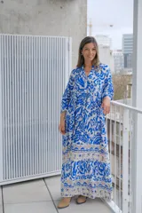 Vestido largo de corte holgado con estampado floral en tonos azul y blanco. Tiene cuello en V, mangas largas y falda con volantes.