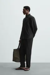 Pantalón negro de corte regular fit, con bolsillos laterales y bolsillos traseros de vivo. Presenta un bajo con vuelta y cierre frontal con cremallera y botón.