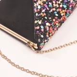 Clutch negro rectangular con cierre dorado y solapa con apliques multicolores. Incluye cadena dorada extraíble.