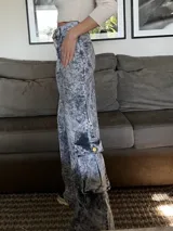 Pantalón jean cargo de pierna ancha y tiro alto, con proceso de lavado artesanal que hace que cada prenda sea única. Presenta bolsillos laterales con solapa y botón.