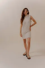 Vestido corto tejido color beige, sin mangas y con cuello redondo.