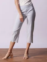 Pantalón capri marca Zac & Rachel, confeccionado en gabardina elastizada a rayas verticales celestes y blancas. Presenta pretina ancha elastizada y ruedo con bordado floral.