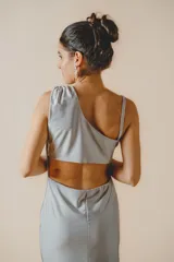 Vestido largo plateado de corte ajustado, con escote asimétrico, espalda descubierta y tajo lateral.