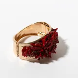 Brazalete rígido dorado con incrustaciones de coral rojo.