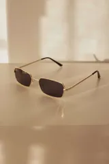 Lentes de sol con armazón rectangular metálico color dorado y lentes oscuras con protección UV400.