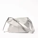 Bolso tipo hobo de cuero sintético plateado con textura granulada, cierre superior con cremallera y correa de hombro ajustable.
