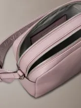 Bandolera rectangular pequeña de cuero sintético color lila con logo CK grabado al frente, cierre superior con doble cremallera y correa de tela ajustable con logo.