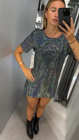 Vestido corto de manga corta, corte recto y ajustado al cuerpo, confeccionado en tejido con lentejuelas holográficas que reflejan múltiples colores.