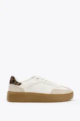Zapatillas deportivas blancas con suela marrón en contraste y detalle de estampado animal en la parte trasera.