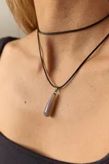 Gargantilla con tira de cuero negro y dije de piedra natural azul en forma de gota.