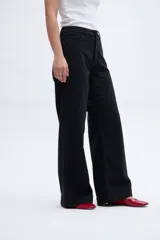 Pantalón jean negro de corte holgado con pierna ancha y tiro medio. Cierre frontal con botones a la vista.