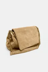 Bolso de hombro color beige, confeccionado en piel de serraje. Tiene correa metálica con detalles, pespuntes en el cuerpo, múltiples bolsillos con cierre de cremallera metálica, cierre imantado y solapa.